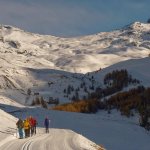 Incrocio tra fondista e racchettisti con a destra la cappella di Clausis